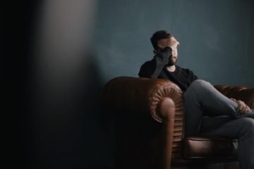 a man holds his head while sitting on a sofa, Functional analytic psychotherapy