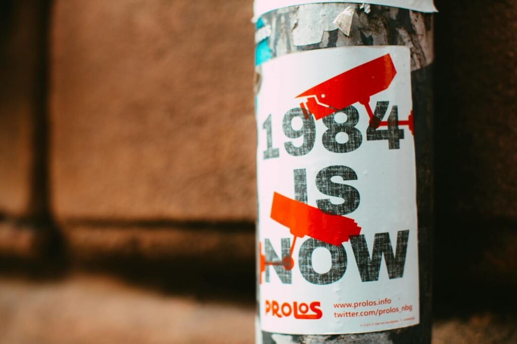 Street poster with '1984 is Now' theme highlighting surveillance in urban setting.