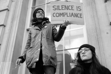 Silence is compliance - A protester with a message standing on a window ledge in Whitehall.