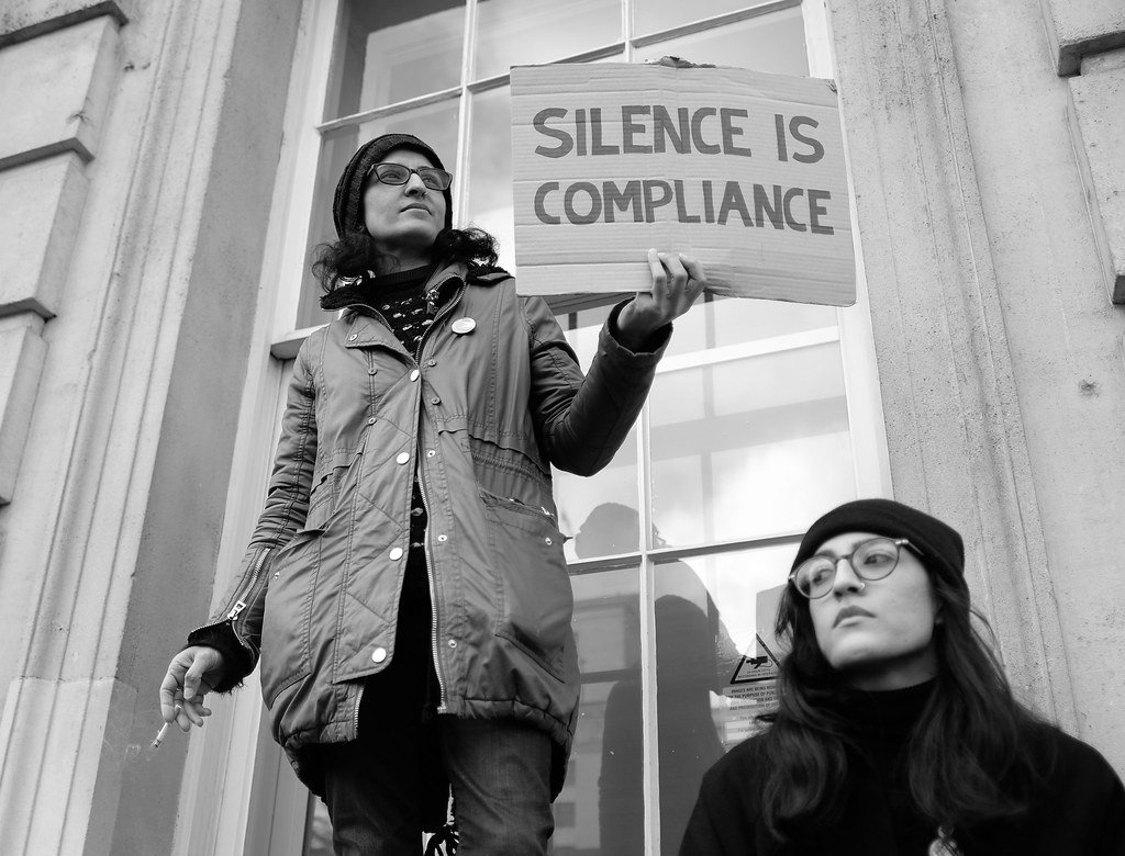 Silence is compliance - A protester with a message standing on a window ledge in Whitehall.