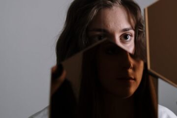 A unique portrait of a woman reflected in a broken mirror, evoking emotion and introspection.