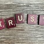 trust spelled with wooden letter blocks on a table