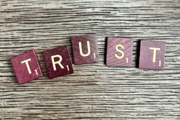 trust spelled with wooden letter blocks on a table
